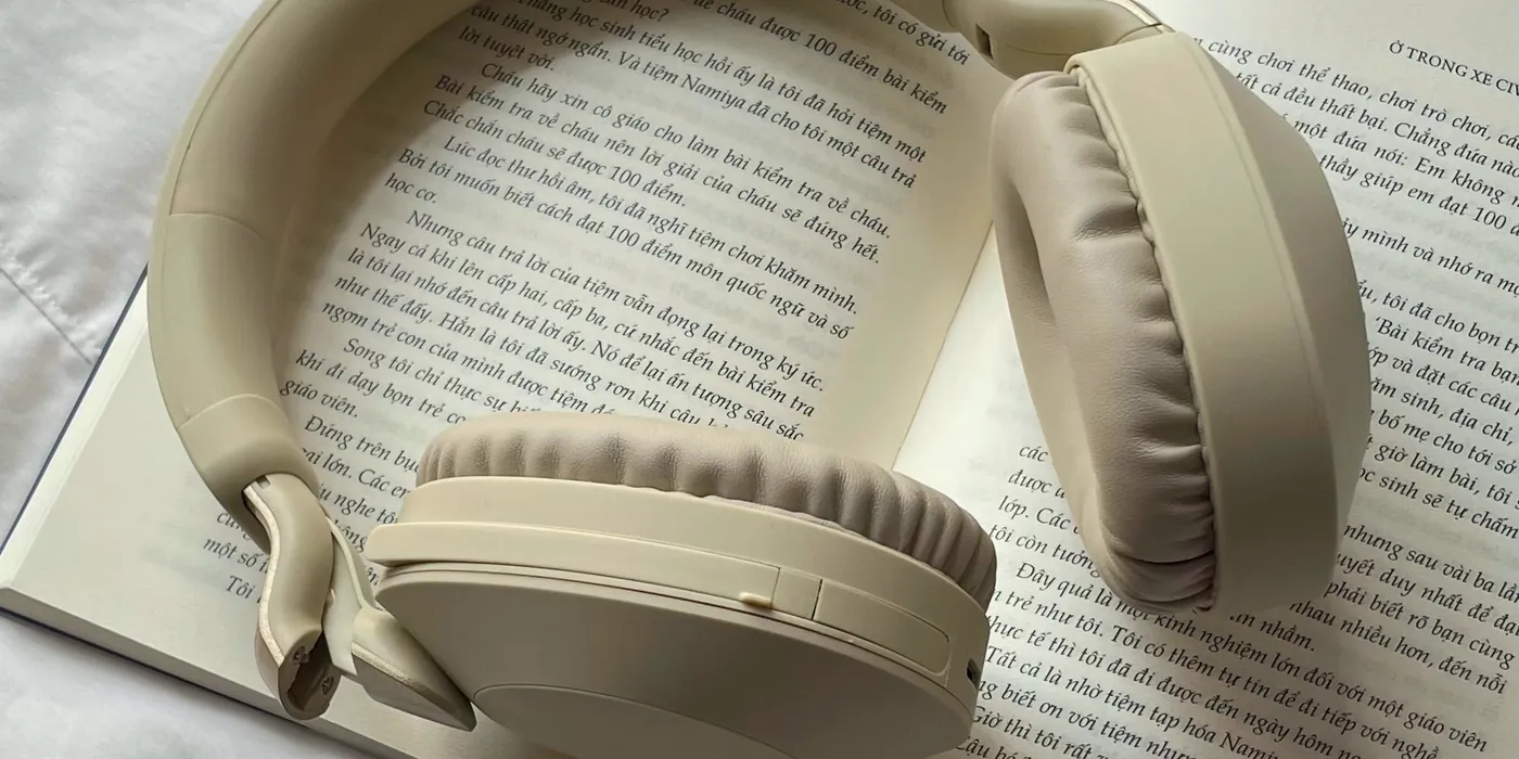 Casque audio crème posé sur un livre ouvert