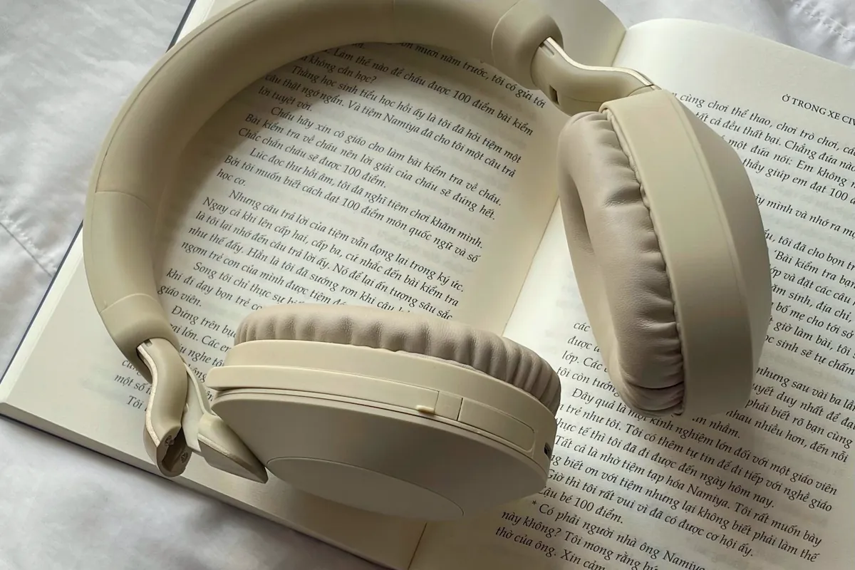 Casque audio crème posé sur un livre ouvert