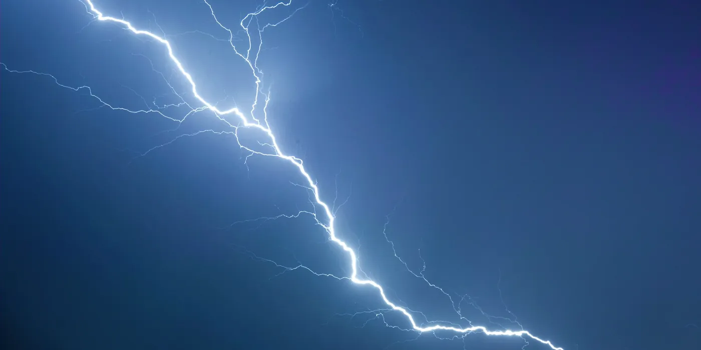 Un éclair blanc ramifié sur un ciel bleu sombre