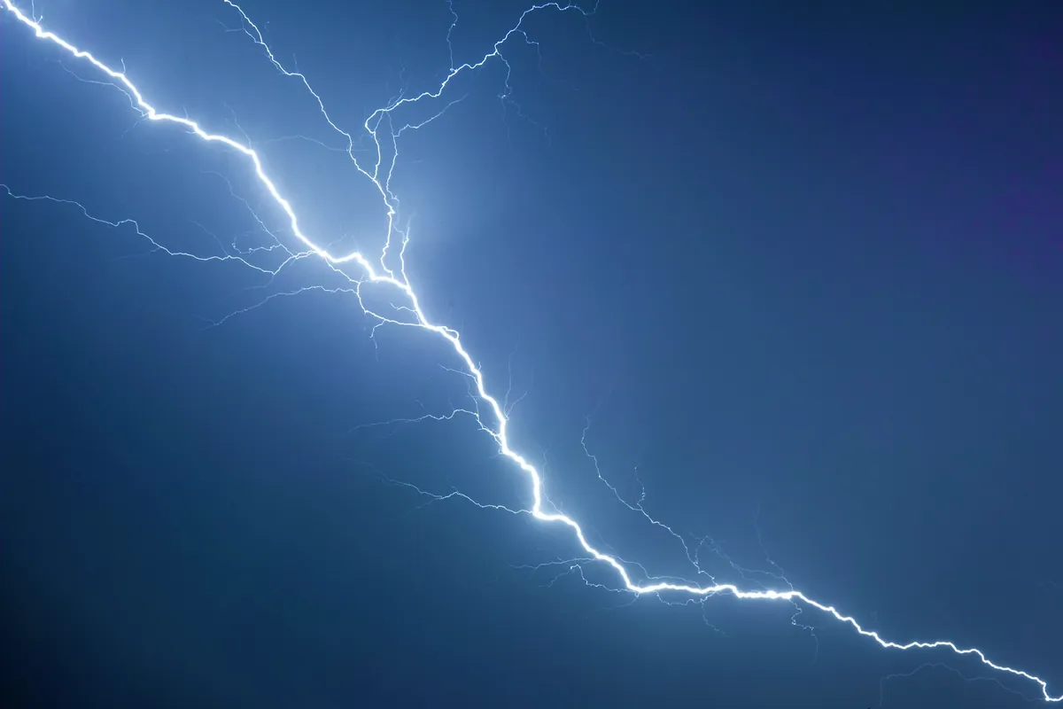 Un éclair blanc ramifié sur un ciel bleu sombre