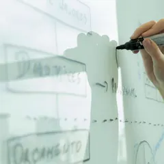Une main trace un schéma au feutre sur un tableau blanc