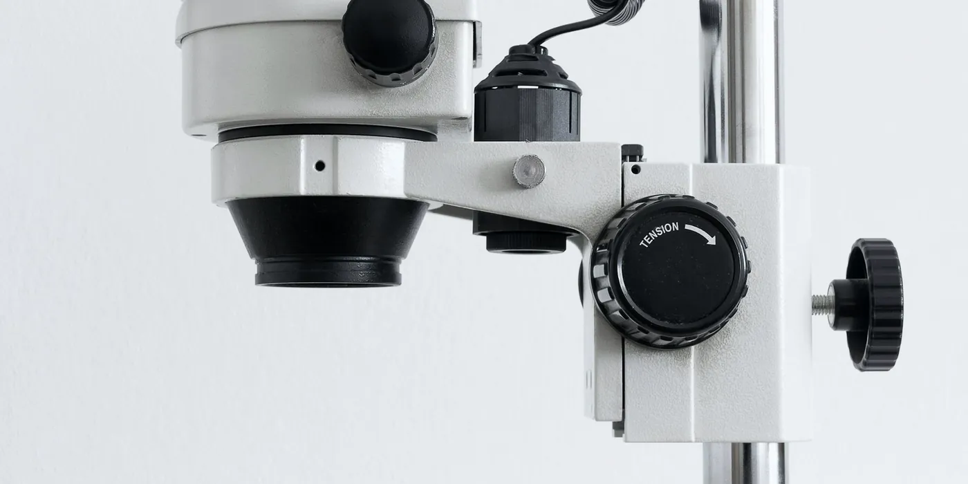 Microscope blanc sur pied, devant un mur clair