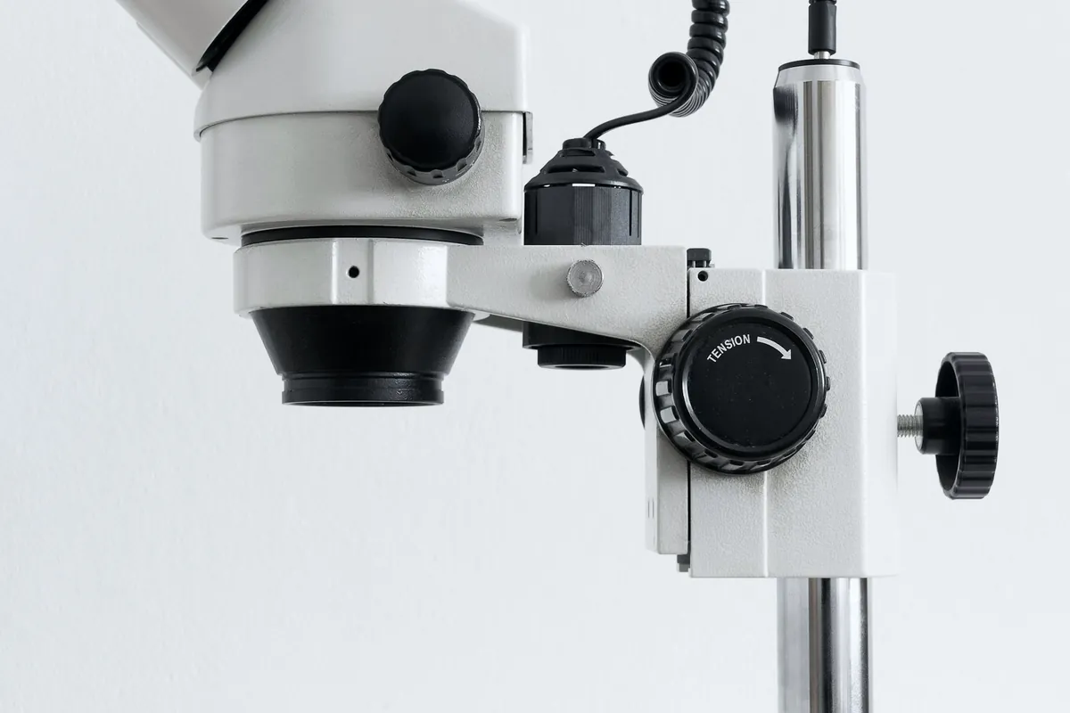 Microscope blanc sur pied, devant un mur clair