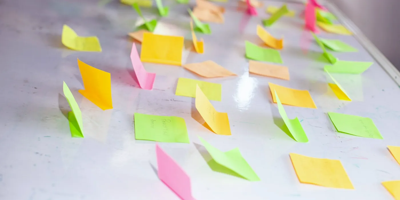 Notes adhésives colorées alignées sur un tableau blanc