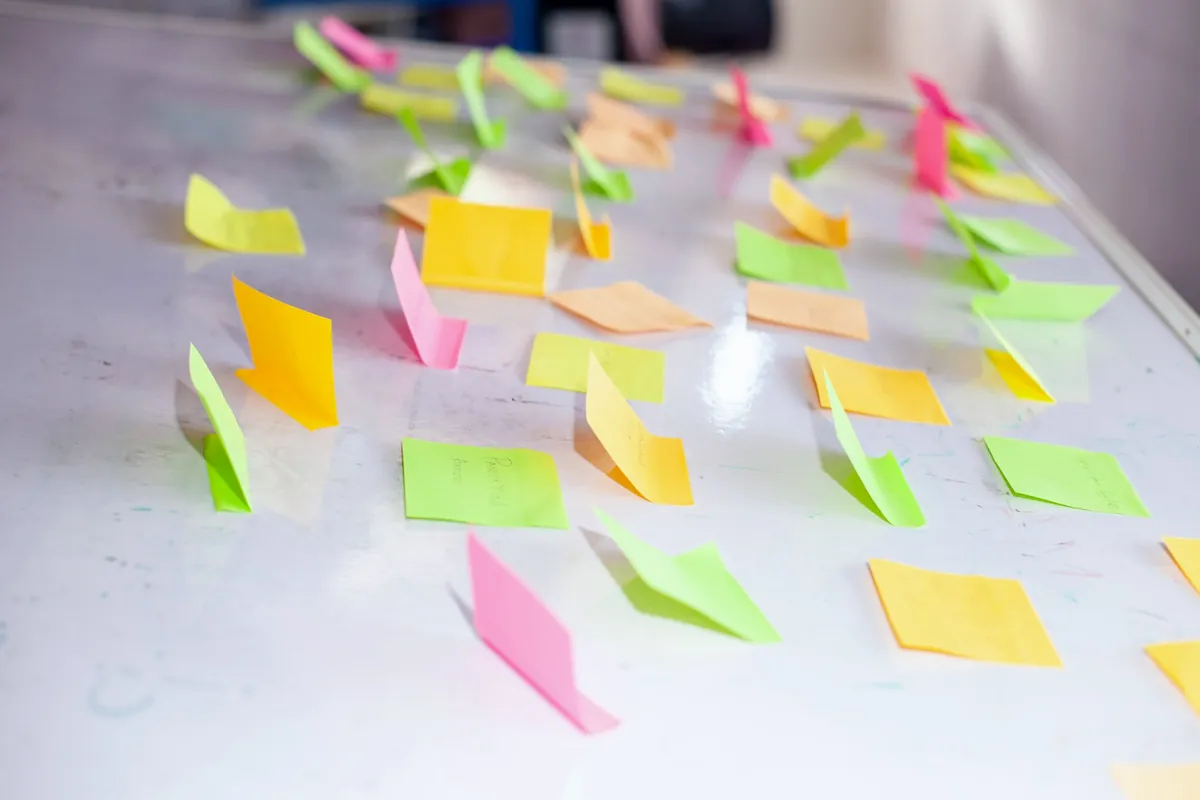 Notes adhésives colorées alignées sur un tableau blanc