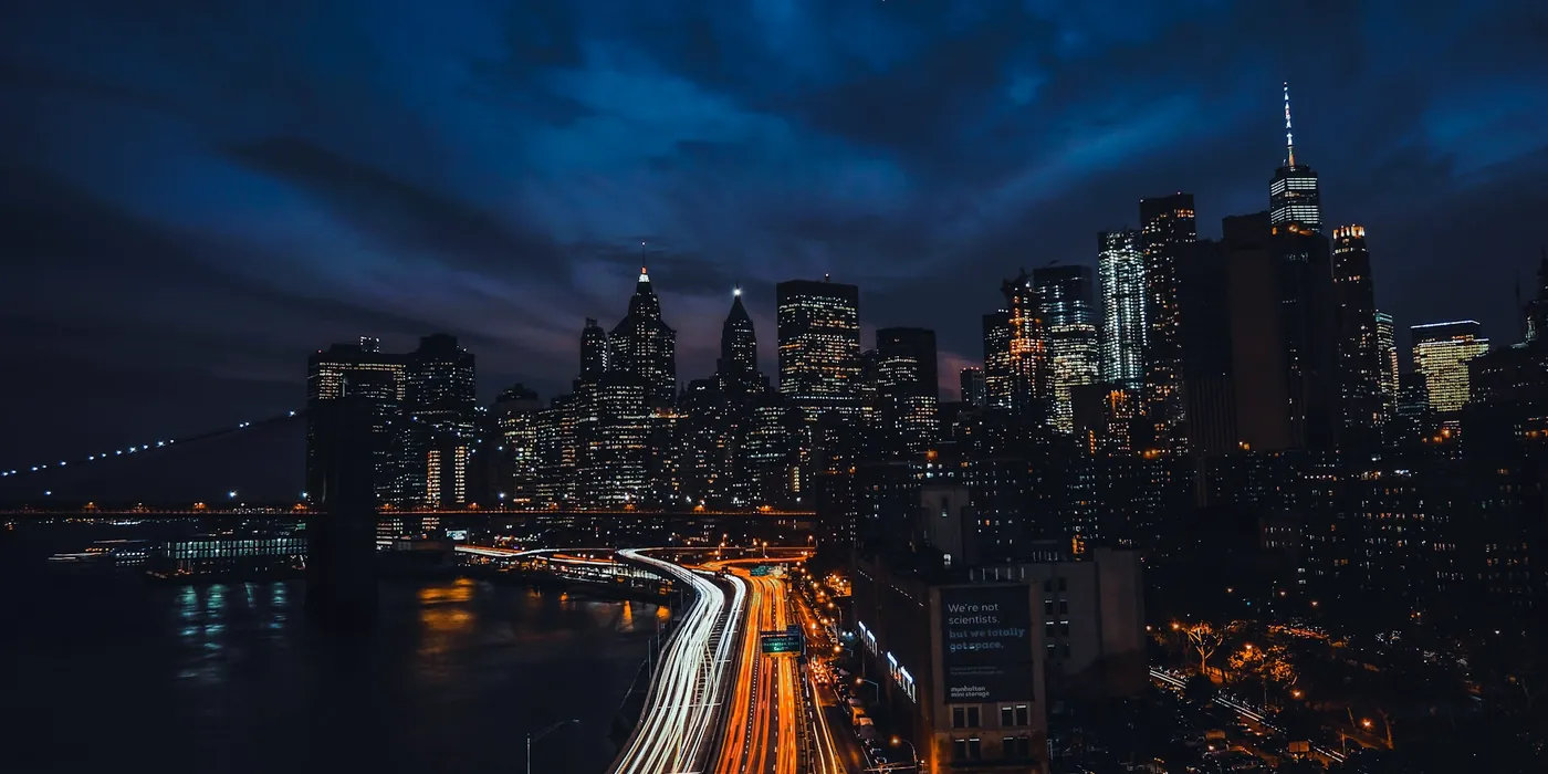 Traînées de lumière sur une autoroute devant une ville la nuit