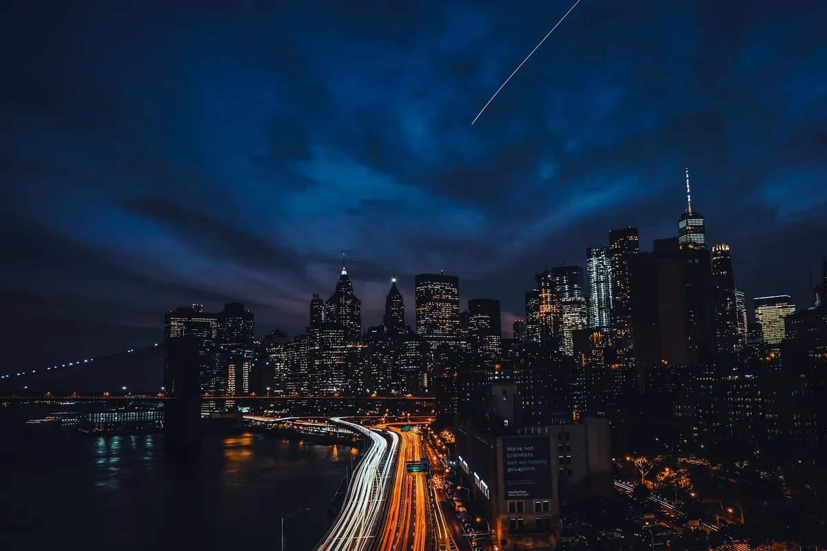 Traînées de lumière sur une autoroute devant une ville la nuit